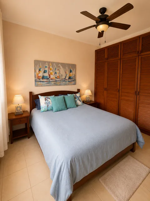 Bedroom 2 with a queen bed, sailboat artwork, and a built-in louvered wood wardrobe closet
