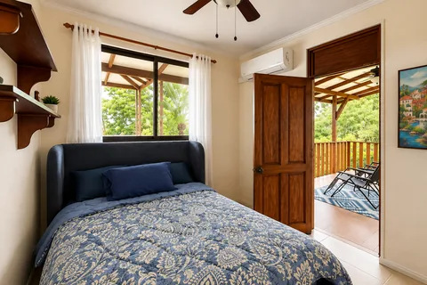Bedroom 4 with a full-size bed and a door opening onto a shared balcony with jungle views