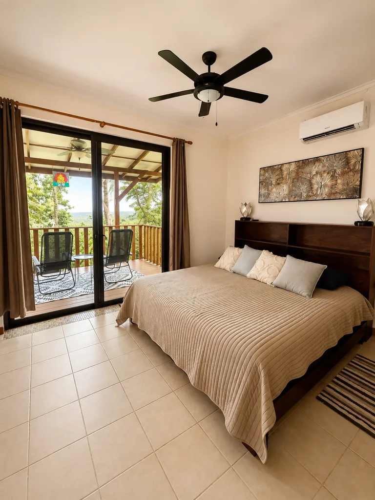 King bedroom with sliding doors opening onto a private balcony with jungle and hillside views