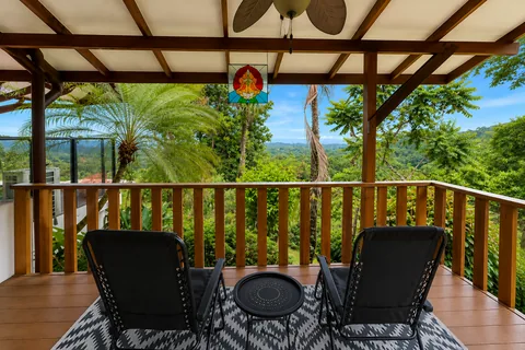 Master bedroom's private terrace, framed by wood beams and stained glass, overlooking the jungle