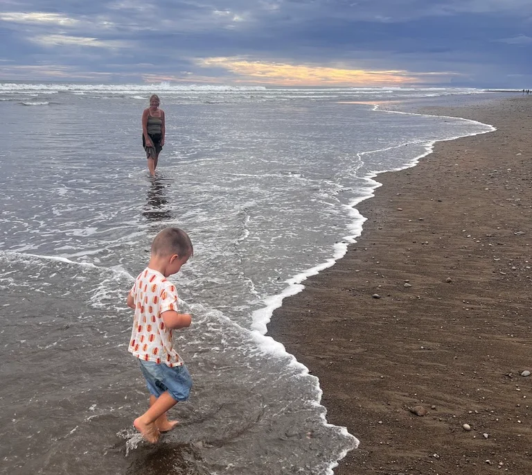 A family wading in the shallows at Playa Dominical, Costa Rica at sunset