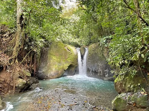 A jungle waterfall near Ojochal, Costa Rica flowing into a turquoise pool, surrounded by lush green-season rainforest