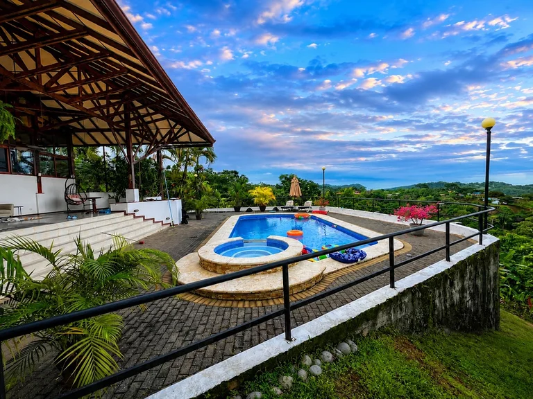 Casa Cascada’s pool and covered terrace overlooking the jungle and Pacific coastline near Ojochal, Costa Rica, under a dramatic dusk sky