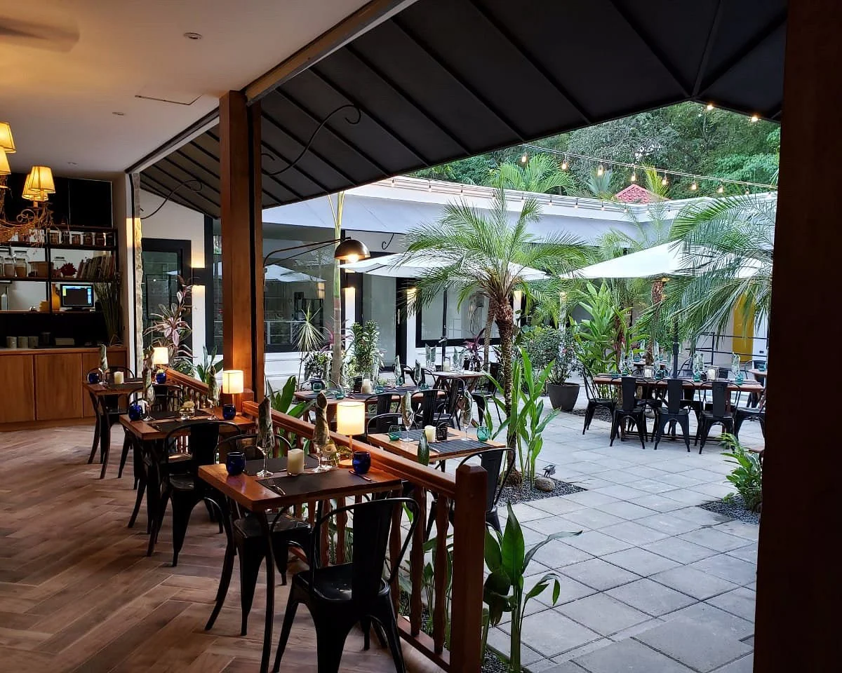 Evening dining at Citrus restaurant in Ojochal, Costa Rica — an open-air covered courtyard with candlelit tables, string lights and palm trees