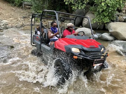 A red side-by-side ATV crossing a jungle river during a Uvita-area 4x4 tour