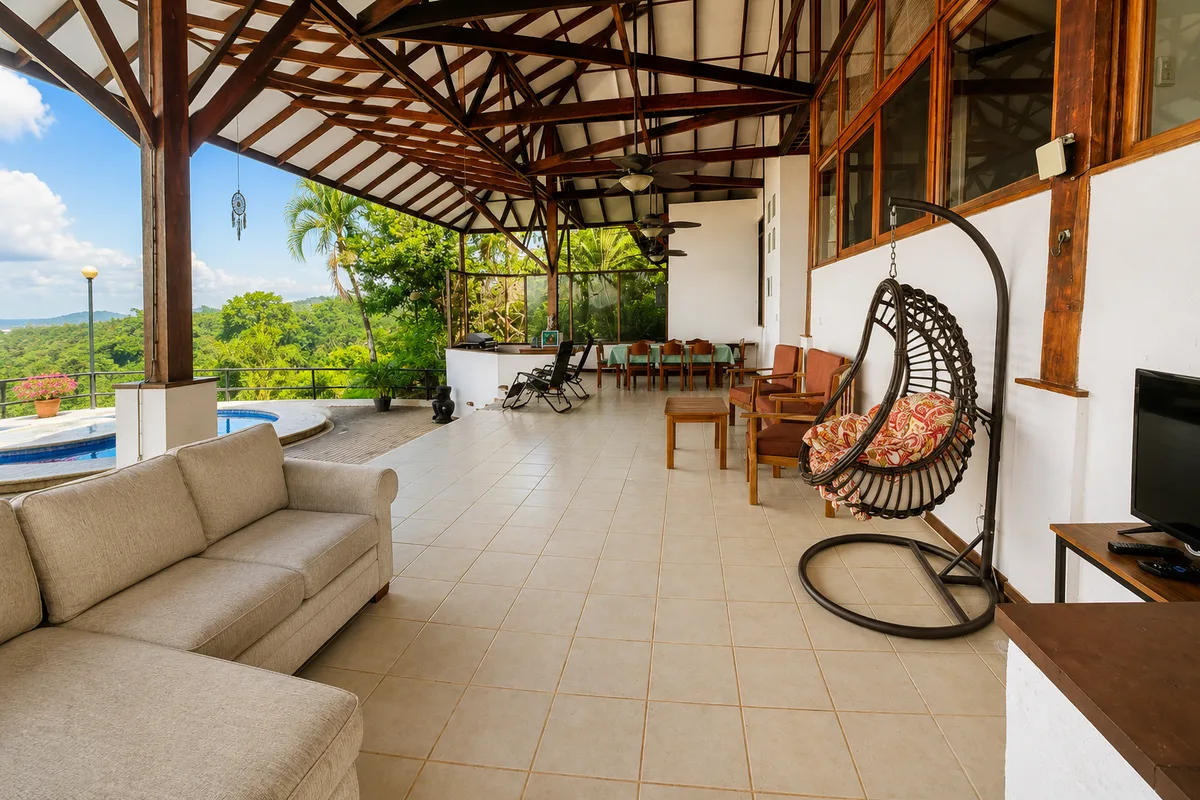Expansive covered terrace at Casa Cascada with sectional sofa, hanging egg chair, and jungle view