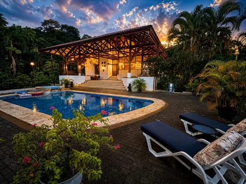 Casa Cascada's pool and illuminated covered terrace at dusk with a colorful sky overhead