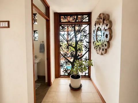 Hallway with a decorative tree-branch window screen, a potted plant, and the half bath visible through the doorway