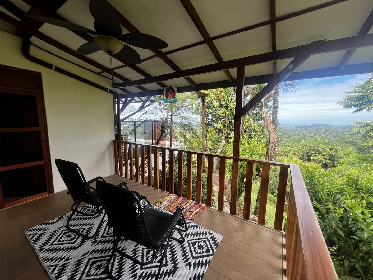 A covered balcony with lounge chairs overlooking the jungle-covered hills and Pacific Ocean near Ojochal, Costa Rica